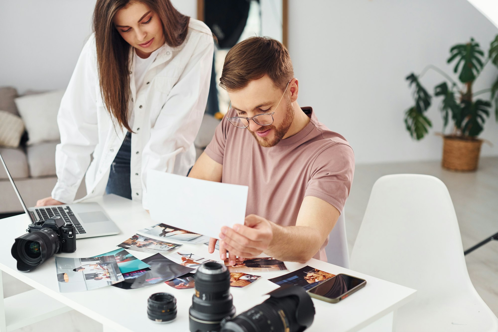 Two photographers in casual clothes is working indoors at daytime